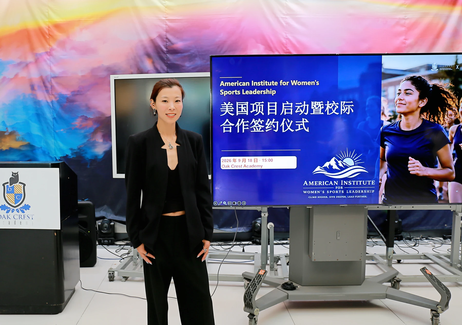 Hang Gao beside the display for the Institute’s September 18, 2026 launch at Oak Crest Academy