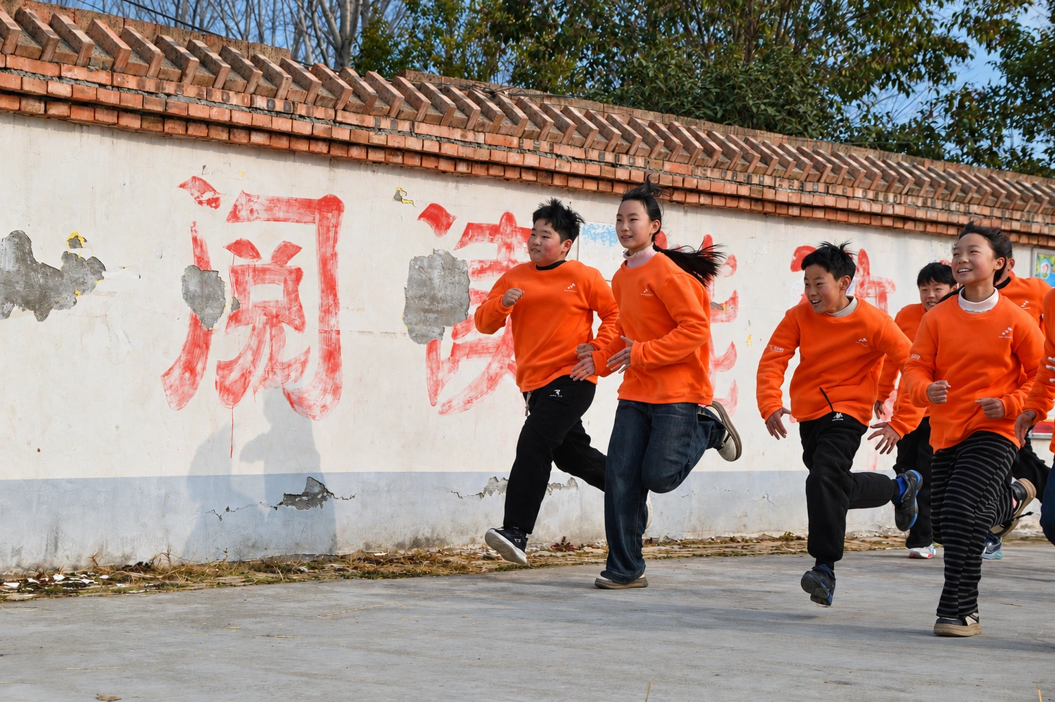 Students in orange sweatshirts running together outdoors